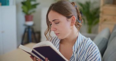 Evde kitap okurken edebi yolculuğunun sayfalarına dalmış bir kadının odaklanmış yüz ifadesini gösteren detaylı bir yakın çekim.