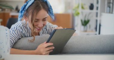 Bir kadın evinde rahatlıyor, dijital tabletindeki internet ve sosyal medyayı karıştırıyor, kendi mekanının rahatlığıyla bağlanıyor ve eğleniyor.