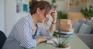 Evdeki bir masada oturan bir kadın, düşünceli bir ifadeyle öğrenmeye derinden bağlı. Ev temelli eğitimi, uzaktan çalışmayı veya kendini geliştirme kavramlarını resmetmek için ideal