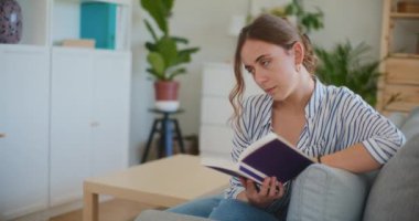 Evde tek başına ders çalışırken melankolik görünen bir öğrenci yalnızlığın ortasında kendini bir kitaba kaptırmış.