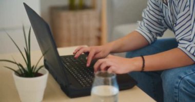 İş kadını dizüstü bilgisayarda yazı yazıyor, e-posta hazırlıyor ve evden iş stratejisi geliştiriyor.