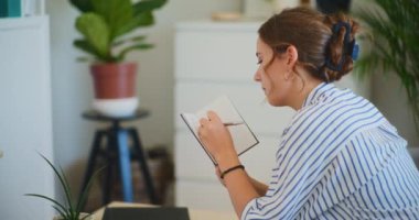 Başarısız ve ümitsiz bir kadın oturma odasındaki not defterine notlar yazar.