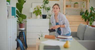 Odaklanmış bir kadın özenle ev masasında belge arıyor.