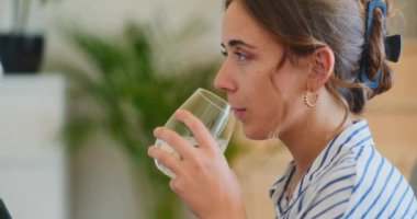 Bir kadın bardaktan su içerken görülüyor.