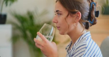 Olumlu ve gülümseyen bir kadın bir bardak sudan ferahlatıcı bir içecek alır.