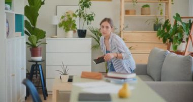 Odaklanmış bir kadın özenle ev masasında belge arıyor.