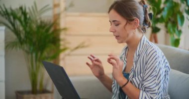 Nişanlı ve odaklanmış bir iş kadını, uzaktan çalışırken bilgisayarında bir video konferansı düzenliyor.