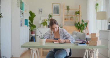 Bir kız öğrenci, öğrenim faaliyetlerini evinin rahatlığından öğrenir ve akademik uğraşlara odaklanır.