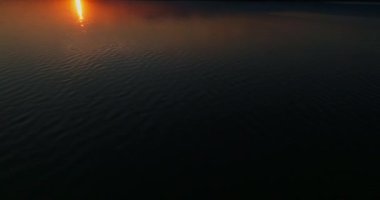 Gölün üzerinde altın bir günbatımının güzel ve şaşırtıcı manzarası