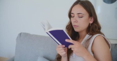 Kadın bir kitapla rahatlar, derin bir odak ve zevk gösterir.