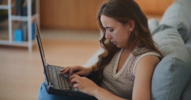 Kanepede dizüstü bilgisayarla çalışan bir kadın e-posta yazıyor.