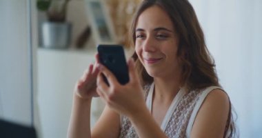 Akıllı telefonlara göz atan bir kadın evden online alışveriş yapıyor.