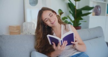 Kadınlar rahat bir kanepede kitap okurken neşeyle gülümserler.