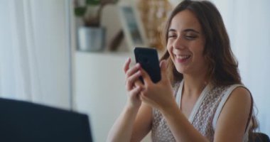 Gülümseyen ve akıllı telefondan online alışveriş yapan olumlu bir kadın.