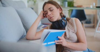 Kadın okumayı bitirir, kulaklık takar ve rahatlamak için müzik dinlemeye başlar.