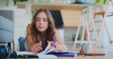 Kadın evde yerde yatıyor, bir kitap açıyor ve bilgi arıyor, sınavlara çalışıyor.