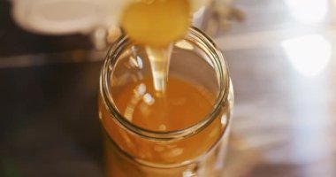 Taze altın kokulu sağlıklı vitamin dolu kavanoza dökülen doğal bal.