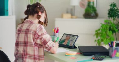 Genç öğrenci dijital tablet kullanarak çevrimiçi öğretmenlik yapıyor, kişisel rehberlik ve destek alıyor