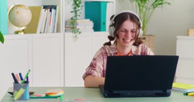 Mutlu öğrenci bilgisayarında uzaktan çalışmayı müzik dinlemekle birleştiriyor, öğrenme deneyiminin tadını çıkarıyor.
