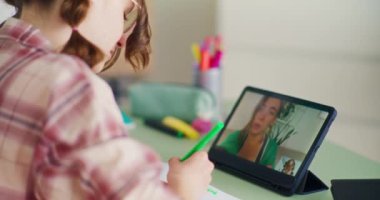 Genç öğrenci uzak çevrimiçi derslere katılmak için dijital tablet kullanıyor ve eğitim içeriğiyle uzaktan yakından ilgileniyor