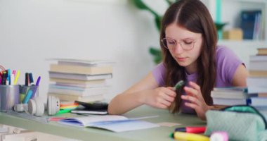 Genç çalışkan öğrenci ödevini yapıyor ve okul eğitimine masasında hazırlanıyor.