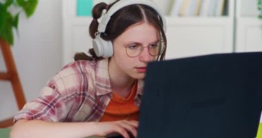 Konsantre olmuş genç kız ödevlerini yapıp aynı anda bilgisayarında online dersler alıyor.