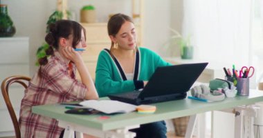 Bir anne, kızına bilgisayarında ödev çözerek ve dijital aletlerden yararlanarak öğrenmesine yardımcı olur.