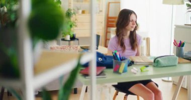 Genç öğrenci çalışma saatine başlamak için çalışma masasındaki matematik defterine bakarak hazırlanıyor.