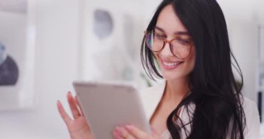 Mutlu bir iş kadını ofiste çalışırken interneti dijital tabletle karıştırır..