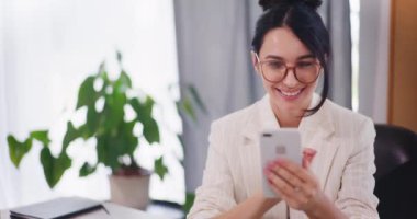 Mutlu bir kadın internetten alışveriş yapar ve akıllı telefonuyla sosyal medyayı karıştırır..