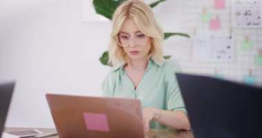 Ofisteki bilgisayarda çalışan bir kadın e-postalara cevap veriyor..