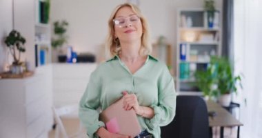 Ofiste elinde dizüstü bilgisayar tutan kendinden emin bir kadının portresi..