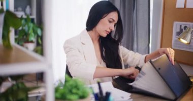 İş kadını finansal belgeleri çıkarıp bir klasörden raporları analiz ediyor..