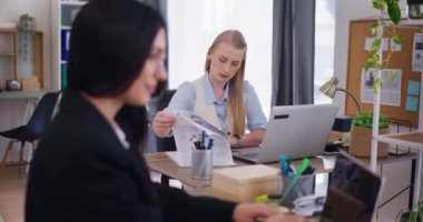 Kadın ofis çalışanları şirketlerin mali raporlarını analiz etmek ve müşteri e-postalarına cevap vermek için ofiste bir dizüstü bilgisayar üzerinde çalışıyorlar..
