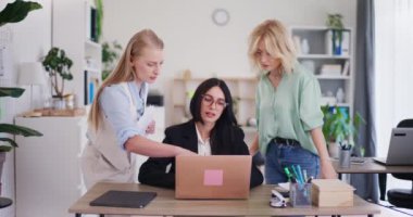 Bir proje sorununu çözmek için üç ofis çalışanından oluşan bir ekip bir dizüstü bilgisayarın üzerine eğilip tartışıyorlar..