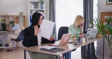 Ofiste bir kadın kendine güvenen, yaratıcı ve belgeleri analiz eden bir proje üzerinde çalışıyor..