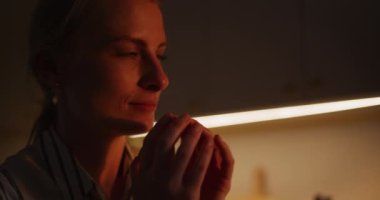 Pencereden süzülen güneş ışınlarına bakan düşünceli bir kadının yüzüne yakından bakın..