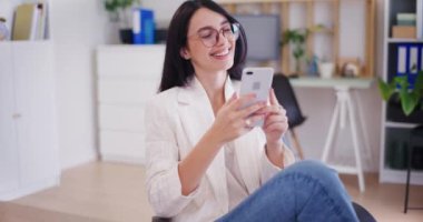 Ofiste çalışırken sosyal medyayı karıştıran mutlu bir iş kadını..