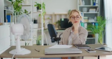 İş kadını ofiste sıcak bir günde serinliyor, bir taraftar üzerine soğuk hava üflüyor..