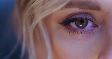 Bir kadın gözlerini açar ve kameraya bakar. Gözün merceğine yakın çekim..