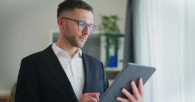 Dijital tablet üzerinde çalışan kendine güvenen bir işadamı.