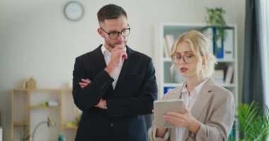 Bir bayan çalışan, şirketin mali sonuçlarını dijital tablette patronuna sunar..