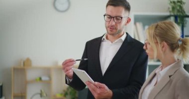 Bir iş adamı, bir meslektaşıyla ofiste bir projeyi tartışıyor..