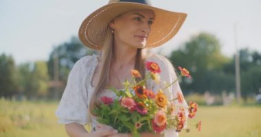 Şapkalı mutlu kadın elinde bir buket taze kesilmiş çiçek tutuyor..