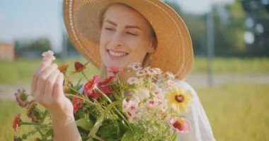 Çiçekleri tutarken gülümseyen hayalperest kadın.