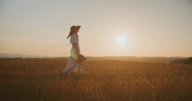 Batan güneşin arka planında yürüyen mutlu kadın..