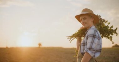 Altın bir günbatımının arka planında mutlu bir kadın çiftçinin portresi.