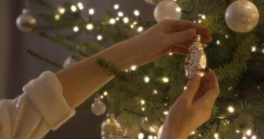 Bir kadının elleri Noel ağacını güzel süslemelerle süslüyor..