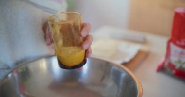 Bir kadının elleri bardağa un dökerken bir yandan da yemek tarifi hazırlarken..