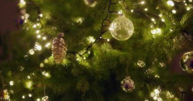 Mücevher ve ışıklardan oluşan güzel bir kompozisyon bir Noel ağacını süslüyor ve neşeli bir ortam yaratıyor..